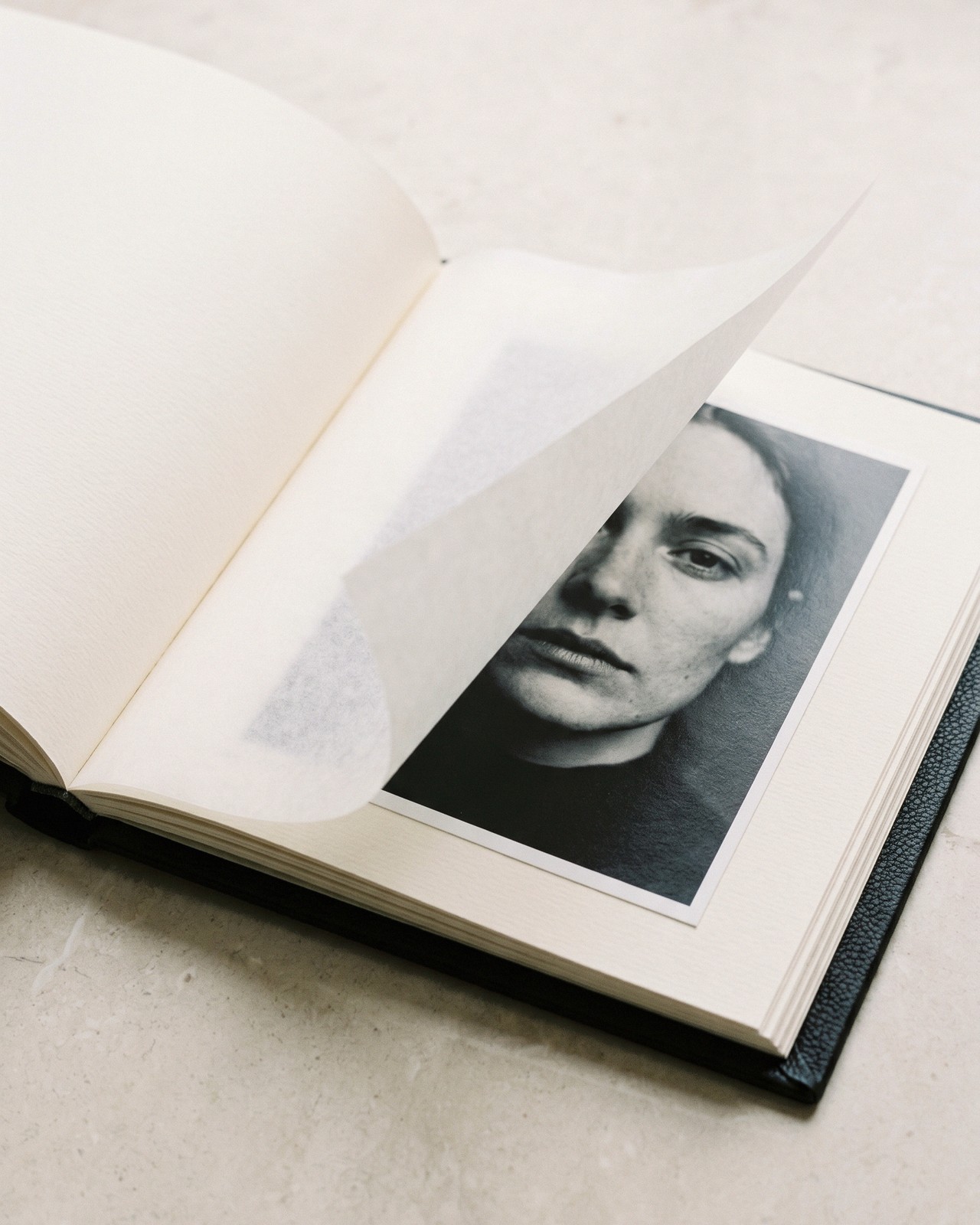L'Album in pelle nera, aperto, con la carta velina sollevata
