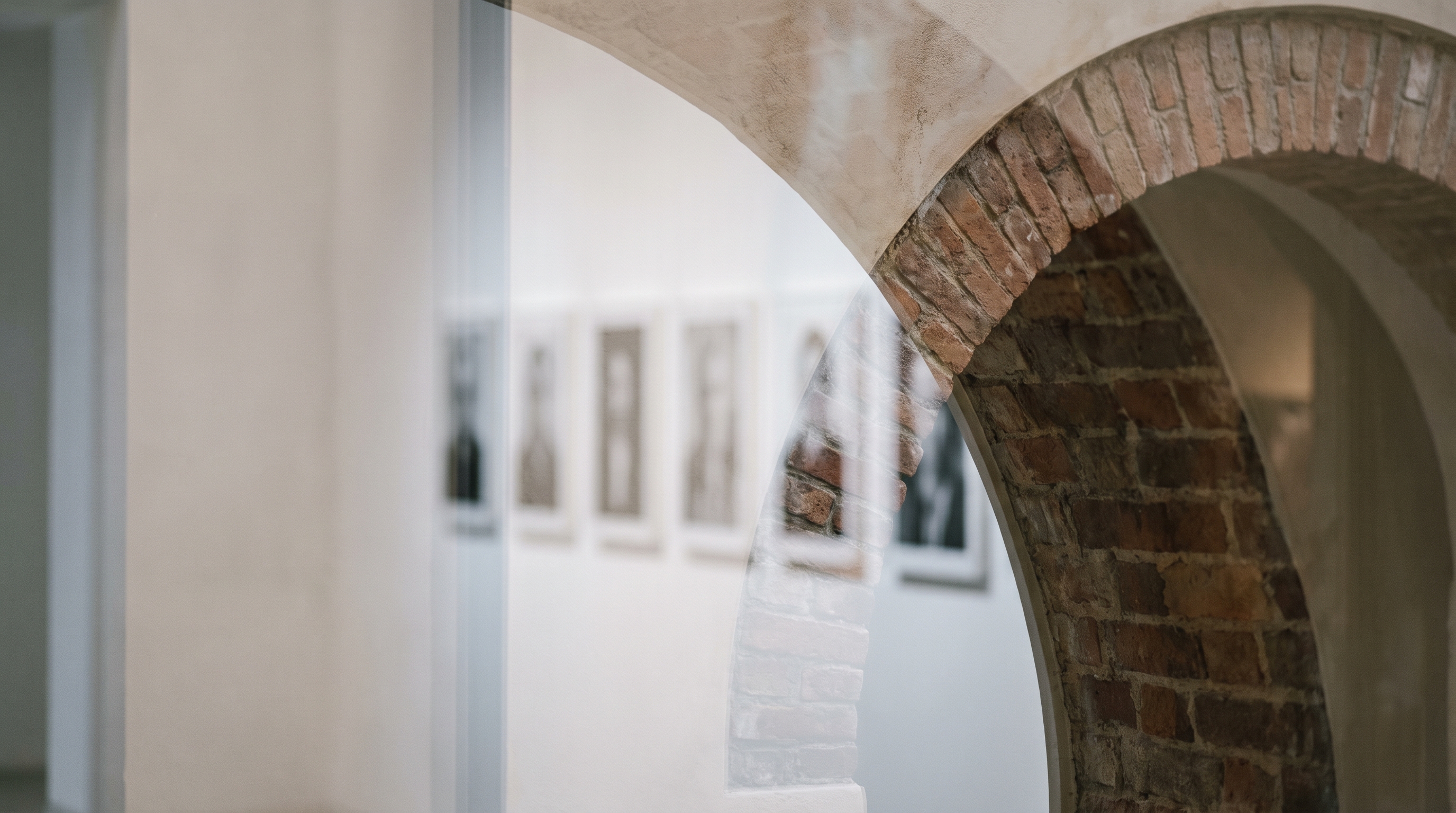 L’arco di mattoni della galleria Magneti®, e oltre la vetrina i ritratti in bianco e nero alle pareti