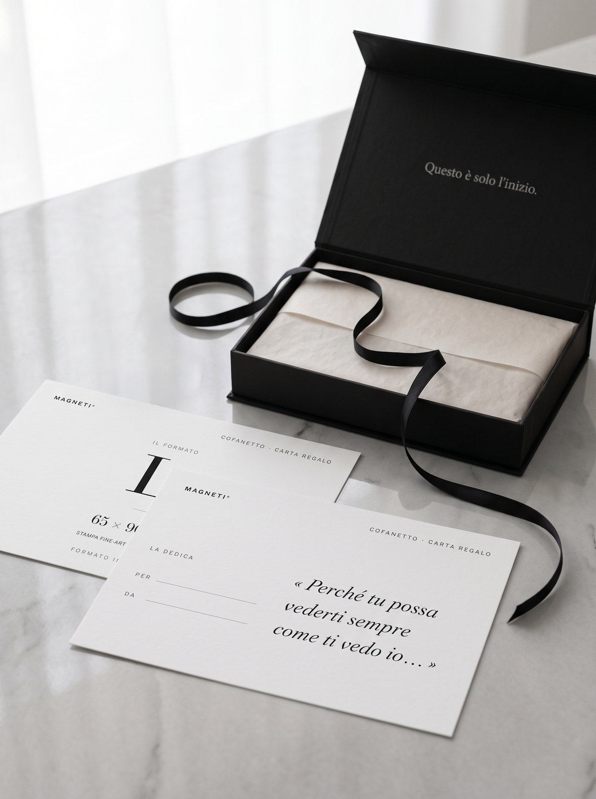 The Magneti® Gift Card case open on marble, with the black ribbon and the dedication cards