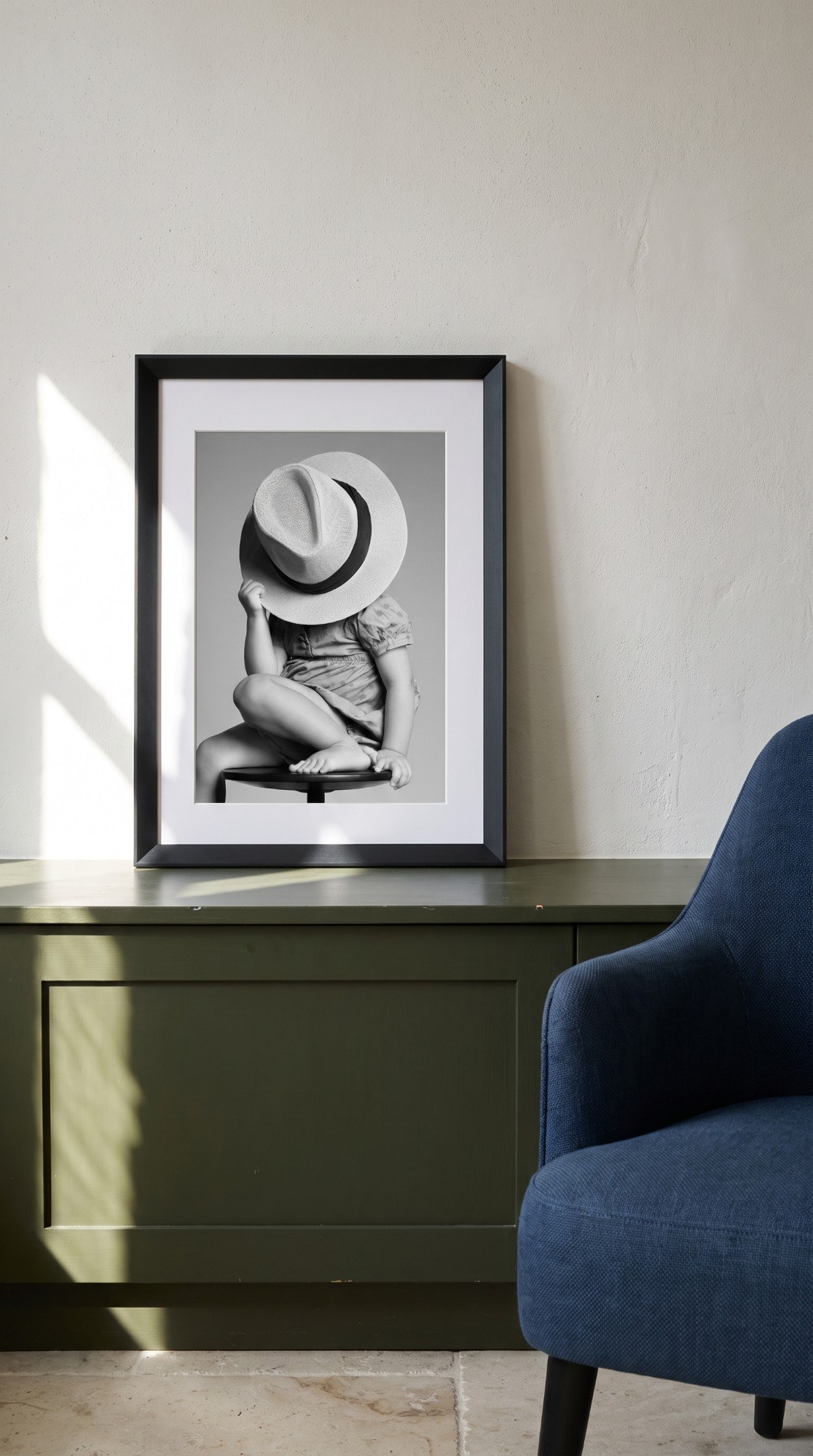 Un Magneti® in cornice nera su una credenza verde: bambina con il cappello