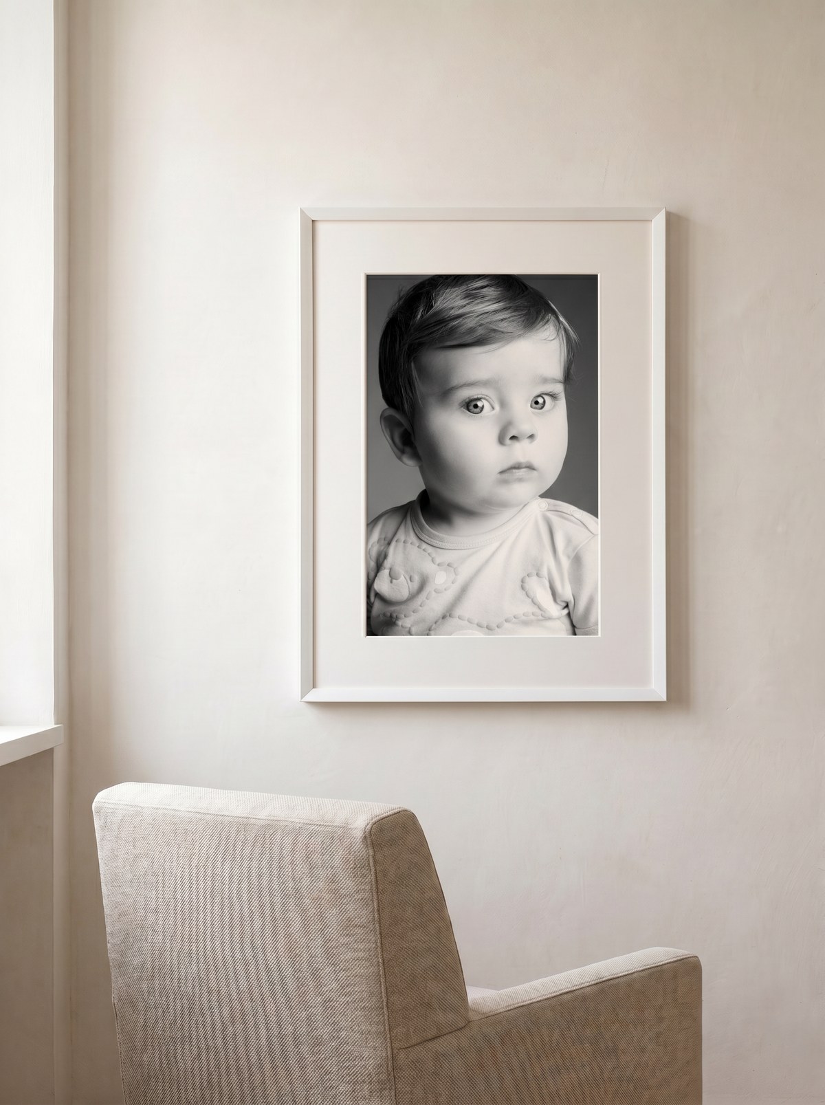 Ritratto Magneti® di un bambino in cornice bianca appesa sopra una poltrona in lino